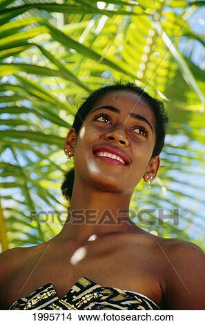 Picture - Fiji, Smiling Young Fijian Woman In Strapless Dress, Palm Fronds In Background. Fotosearch