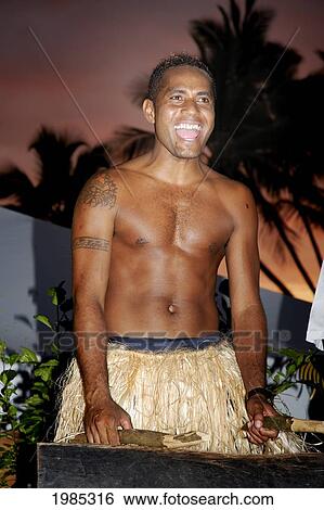Fiji, Viti Levu, Coral Coast, Hideaway Resort, Fijian Drummer In Traditional Grass Skirt In Tropical Setting At Sunset. For Editorial Use Only. View Large Photo Image Stock Photograph - Fiji, Viti Levu, Coral Coast, Hideaway Resort, Fijian Drummer In Traditional Grass Skirt In Tropical Setting At Sunset. For Editorial Use Only.. Fotosearch