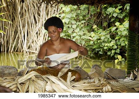 Stock Photo - Fiji, Viti Levu, Coral Coast, Pacific Harbor, Arts Village, Fijian Woman In Open Bure Weaving Palm Leaves. No Model Release. Fotosearch