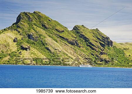 Stock Photo - Fiji, Yasawas, Waya Island, Captain Cook Cruise Ship Passes Dramatic Mountains, View From Ocean.. Fotosearch