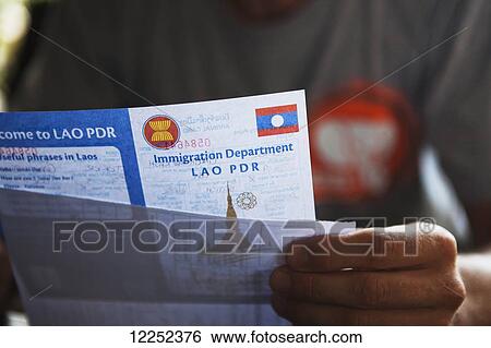Stock Photograph - Filling out the various Visa paperwork to exit Thailand and enter Laos; Chiang Mai, Thailand. Fotosearch