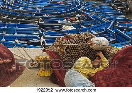 Stock Image - Fisherman Asleep On Fishing Nets. Fotosearch