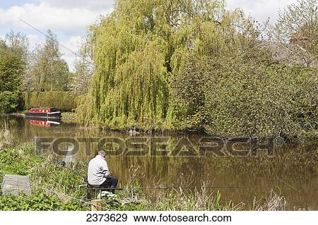 Stock Photo - Fisherman fishing along banks of Kennet and Avon Canal; Hungerford, Berkshire, England. Fotosearch