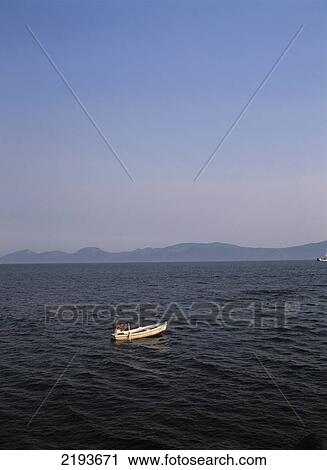 Stock Image - Fisherman Going Out To Sea In Small Rowing Boat At Dusk From Sucaraj Harbour On The Eastern Tip Of Hvar Island, Croatia.. Fotosearch