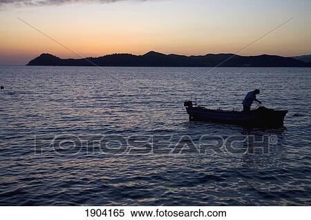 Stock Photography - Fisherman In Boat At Dusk, Lopud, Croatia. Fotosearch