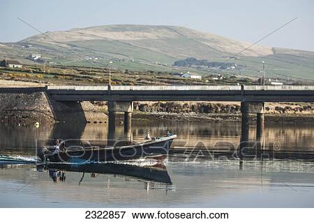 Stock Photo - Fisherman in motorboat trawling on tranquil water; Portmagee, Iveragh Peninsula, County Kerry, Ireland, UK. Fotosearch