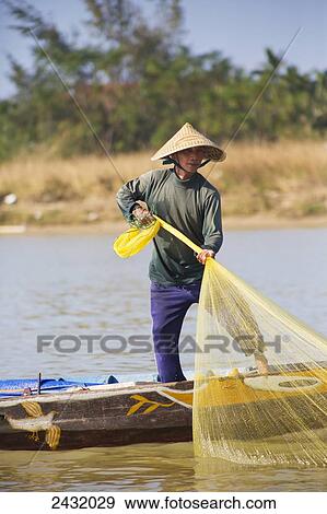 Stock Photo - Fisherman pulling in his net on the Thu Bon River in Hoi An, a UNESCO World Heritage Site; Vietnam. Fotosearch