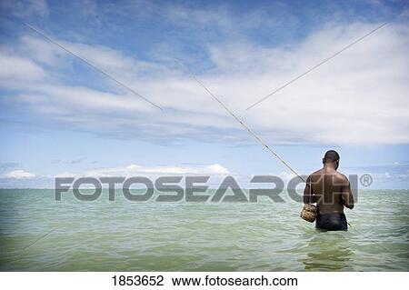 Stock Image - Fisherman Wading Into The Ocean, Brazil. Fotosearch