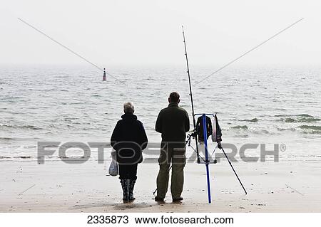 Stock Image - Fishermen Along South Beach; Pembrokeshire Coast Path, Wales, United Kingdom. Fotosearch
