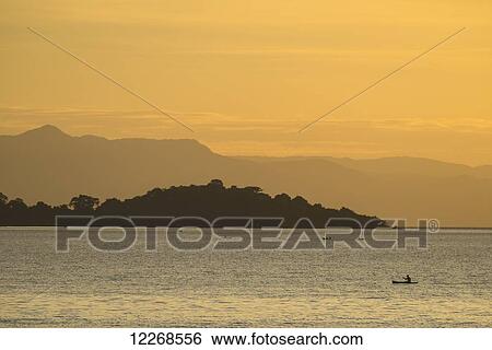 Stock Photograph - Fishermen in dugout canoes coming into Cape Maclear in the evening, Lake Malawi; Malawi. Fotosearch