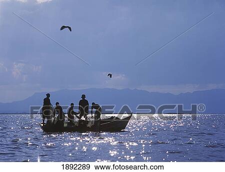 Stock Photo - Fishermen Pulling Fishing Nets On Small Boat On Lake Chilwa. Fotosearch