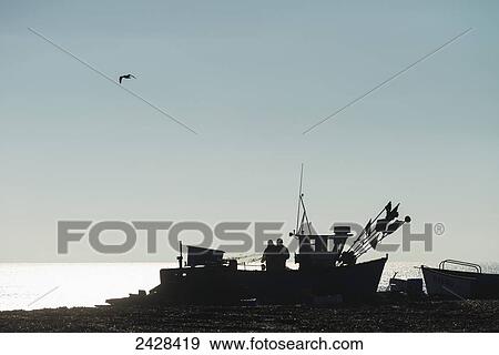 Stock Photo - Fishermen sorting out their nets on boat on Aldeburgh beach; Suffolk, England. Fotosearch