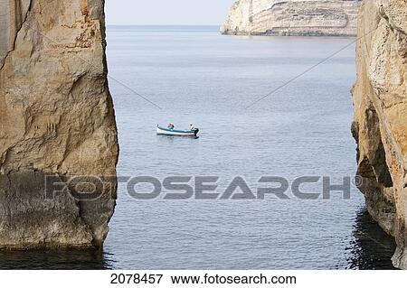 Stock Photo - Fishing Boat By The Azure Window, A Natural Rock Arch, Dwejra Bay, Gozo Island, Malta. Fotosearch
