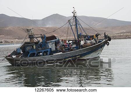 Fishing boat laden down with supplies with barren Moroccon landscape behind; Sidi Ifni, Morocco View Large Photo Image Stock Photography - Fishing boat laden down with supplies with barren Moroccon landscape behind; Sidi Ifni, Morocco. Fotosearch