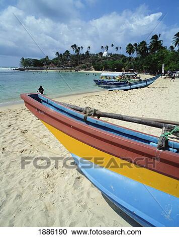 Stock Image - Fishing Boat On Beach With Temple In Background. Fotosearch