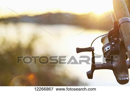 Stock Photo - Fishing rod and tranquil water at sunset; Quebec, Canada. Fotosearch