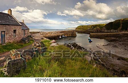 Stock Image - Fishing Traps A House And Boats Mooring On The Coast; Cove Lothian Scotland. Fotosearch