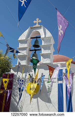 Stock Image - Flags hanging around an old white washed church; Mykonos Town, Mykonos, Cyclades, Greek Islands, Greece. Fotosearch