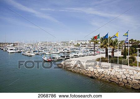 Stock Photograph - Flags Lining The Stone Wall In The Harbour; Lagos Algarve Portugal. Fotosearch
