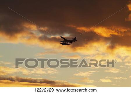 Stock Photo - Floatplane flying in the sunset, North Vancouver, British Columbia, Canada. Fotosearch