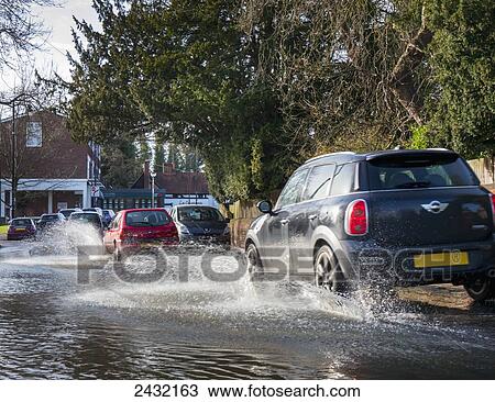 Stock Image - Flood water splashing on the road; Cobham, Surrey, England. Fotosearch