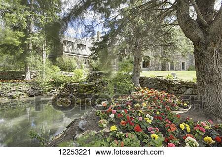 Stock Image - Flowerbed and pond in front of Banff National Park Administration Office; Banff, Alberta, Canada. Fotosearch