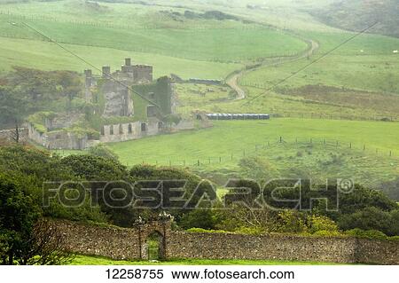 Stock Photography - Foggy green pastures with stone wall and stone ruin castle; Clifden, County Galway, Ireland. Fotosearch