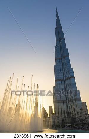 Stock Image - Fountain display in front of the Burj Khalifa at sunset; Dubai, United Arab Emirates. Fotosearch
