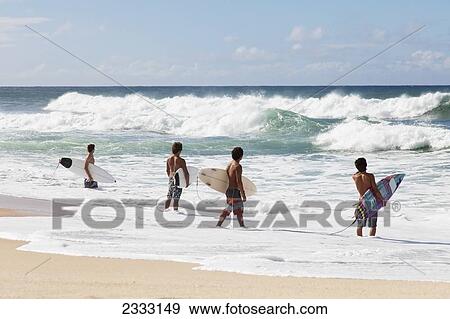 Four young surfers check out the incoming waves; Oahu, Hawaii, United States of America View Large Photo Image Stock Photo - Four young surfers check out the incoming waves; Oahu, Hawaii, United States of America. Fotosearch