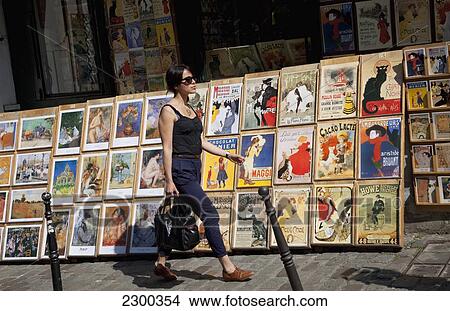 Picture - France, Montmartre; Paris, Woman walking past art stalls. Fotosearch