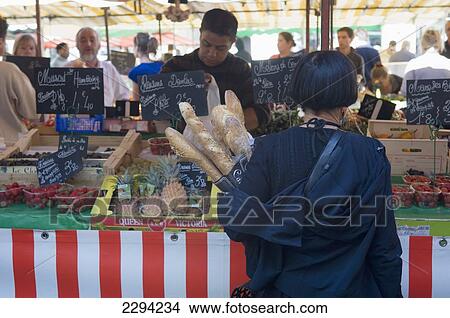 Picture - France, Poitou-Charentes, Woman shopper holding baguettes at market; La Rochelle. Fotosearch
