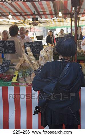Stock Photograph - France, Poitou-Charentes, Woman shopper holding baguettes at market; La Rochelle. Fotosearch