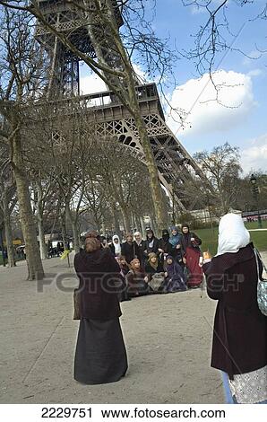 Stock Image - France, Woman Taking Group Photo Of Muslim Women In Front Of Eiffel Tower; Paris. Fotosearch