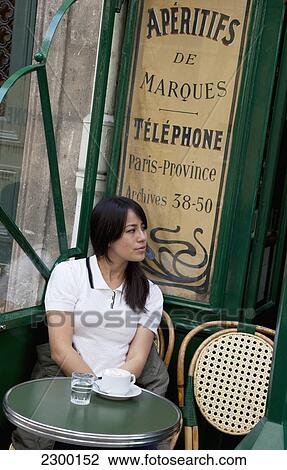 Stock Image - France, Young woman at Parisian Cafe; Paris. Fotosearch