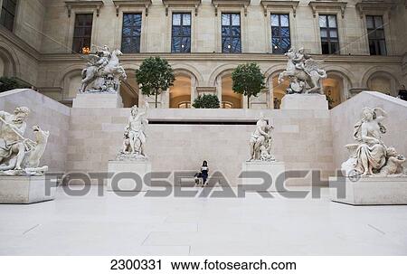 Stock Image - France, Young woman looking at map Louvre Museum; Paris. Fotosearch
