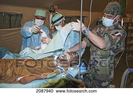 Stock Image - French Medical Team Operates On An 8-Year Old Girl, Just Flown In From The Mountains, In A Field Hospital Outside The Totally Destroyed Muzaffarabad Hospital After The 8 October 2005 Earthquake, Muzaffarabad, Azad Kashmir, Pakistan. Fotosearch