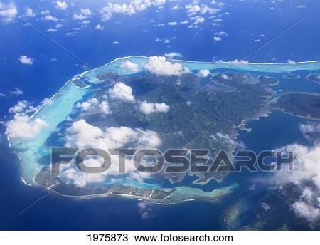 Stock Image - French Polynesia, Aerial Over Atoll, View From Above Small White Clouds Outer Barrier Reef Surrounds Inner Lagoon.. Fotosearch