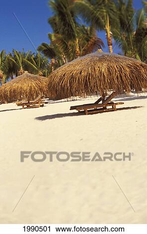 Stock Image - French Polynesia, Beach Chair And Thatched Bungalow On White Sand Beach With Palm Trees. Fotosearch