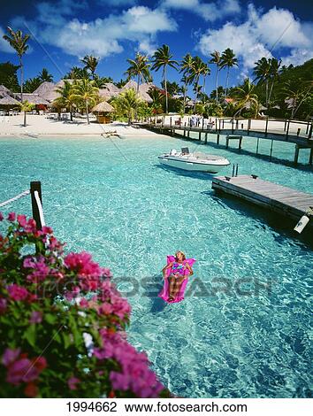 Stock Image - French Polynesia, Bora Bora, Moana Beach Park Royal, Woman On Inflatable Raft In Turquoise Ocean. Fotosearch