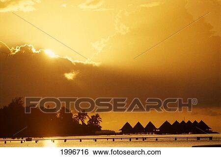 Stock Photograph - French Polynesia, Bora Bora, Sunset Over Hotel Bora Bora Huts, Golden Sun And Sky A56C. Fotosearch