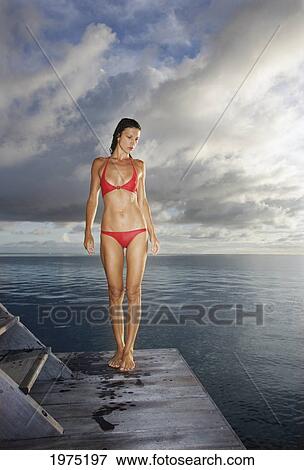Stock Photo - French Polynesia, Moorea, Attractive Young Woman Standing On A Dock After A Swim In The Ocean.. Fotosearch