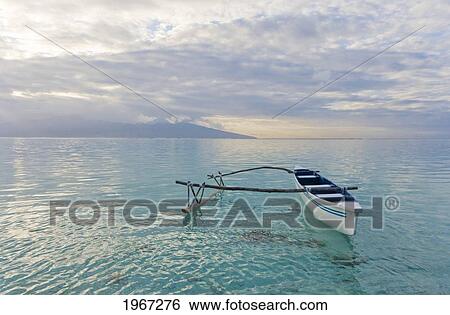 Stock Photograph - French Polynesia, Moorea, Outrigger Canoe On Calm Ocean Water.. Fotosearch