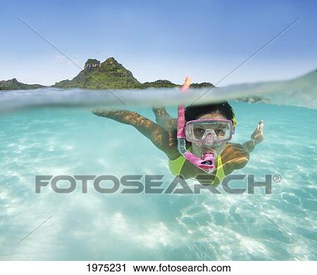 Stock Image - French Polynesia, Moorea, Woman Free Diving In Turquoise Ocean.. Fotosearch