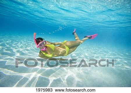 Stock Image - French Polynesia, Moorea, Woman Free Diving In Turquoise Ocean.. Fotosearch