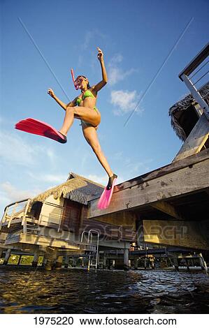 Stock Image - French Polynesia, Moorea, Woman Leaps From Bungalow.. Fotosearch