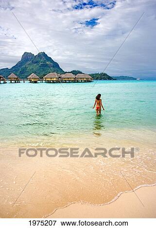 Stock Photo - French Polynesia, Tahiti, Bora Bora, Woman In The Ocean With Bungalows In The Background.. Fotosearch