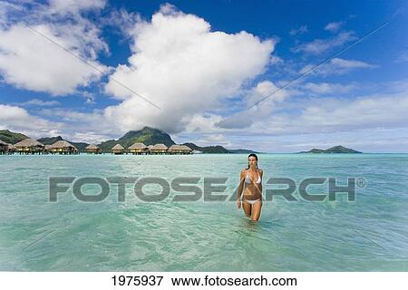 Stock Photo - French Polynesia, Tahiti, Bora Bora, Woman In The Ocean With Bungalows In The Background.. Fotosearch