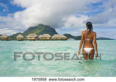 Stock Photo - French Polynesia, Tahiti, Bora Bora, Woman In The Ocean With Bungalows In The Background.. Fotosearch