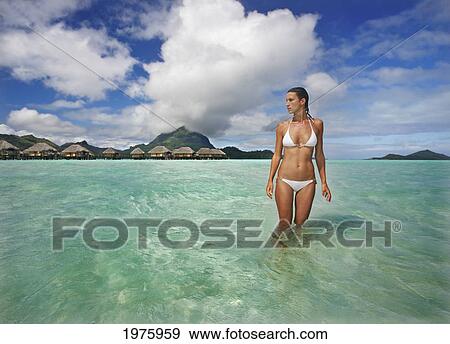 Stock Photo - French Polynesia, Tahiti, Bora Bora, Woman In The Ocean With Bungalows In The Background.. Fotosearch
