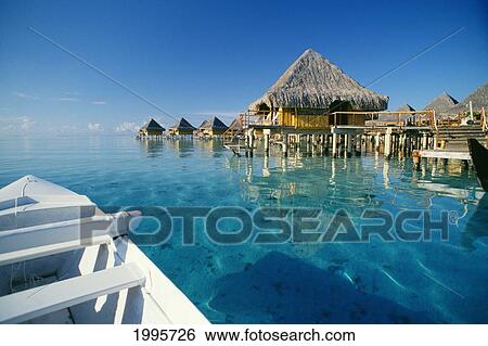 Stock Photograph - French Polynesia, Tahiti, Bora Bora, Moana Beach Hotel Bungalows Seen From Outrigger Canoe. Fotosearch